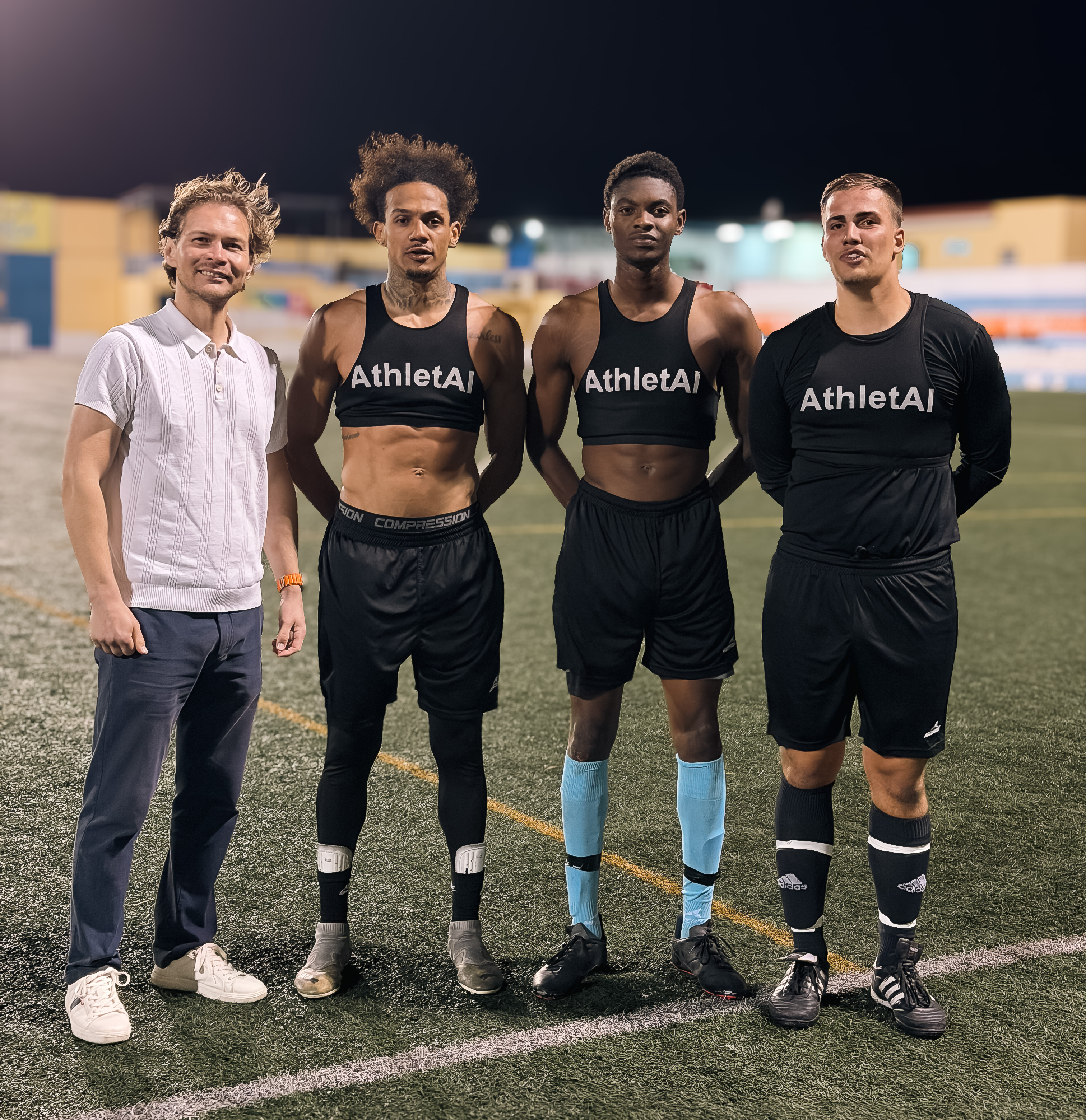 Athletes standing on a football pitch wearing AthletAI vests